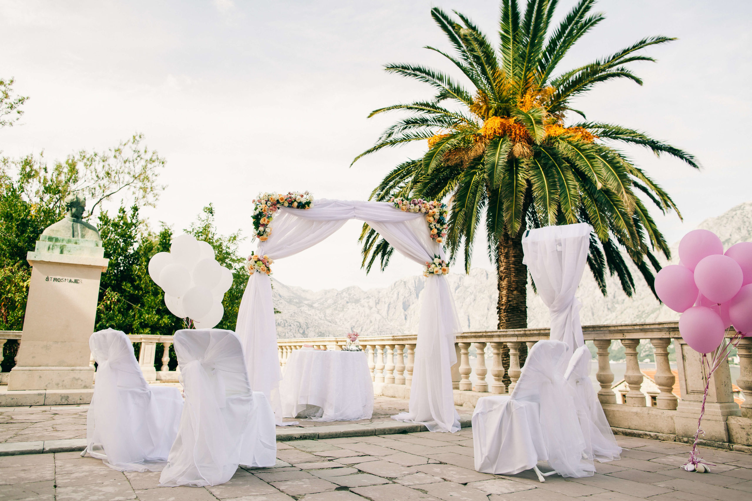 Sunset destination wedding arch on beach white chairs palm trees